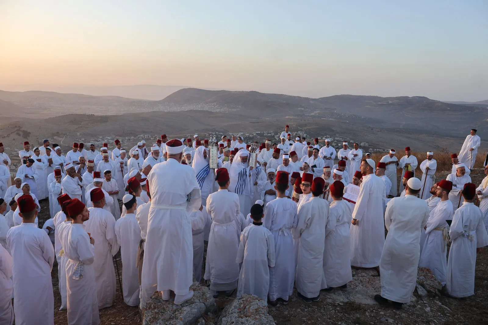 Samaritans in white robes praying on Mount Gerizim at dawn
